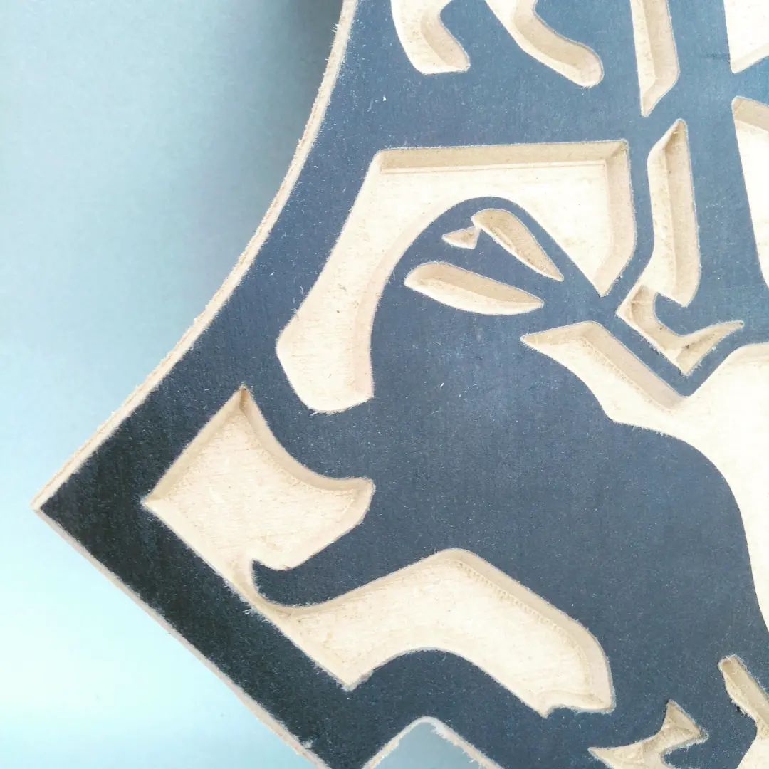 Detail shot of CNC-milled Hogwarts crest — badger quarter